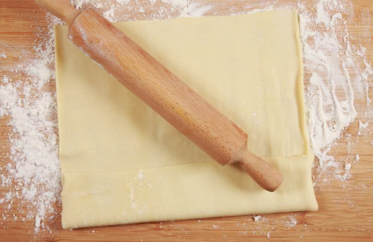 Un rotolo di pasta sfoglia steso su un piano