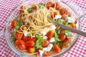 Un piatto di pasta estiva con pomodorini, mozzarella e basilico