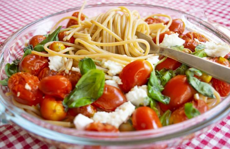 Pasta estiva con pomodorini, mozzarella e basilico appena servita in piatto