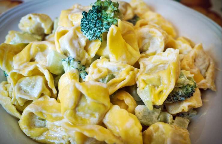 Un piatto di tortellini ai formaggi misti con panna e broccoli