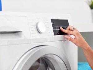 persona pigia un pulsante sulla lavatrice